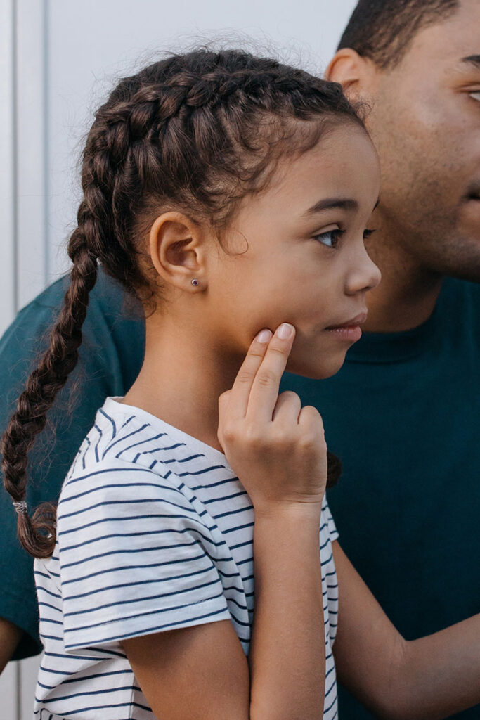 Child touches her jaw while waiting for emergency dental care