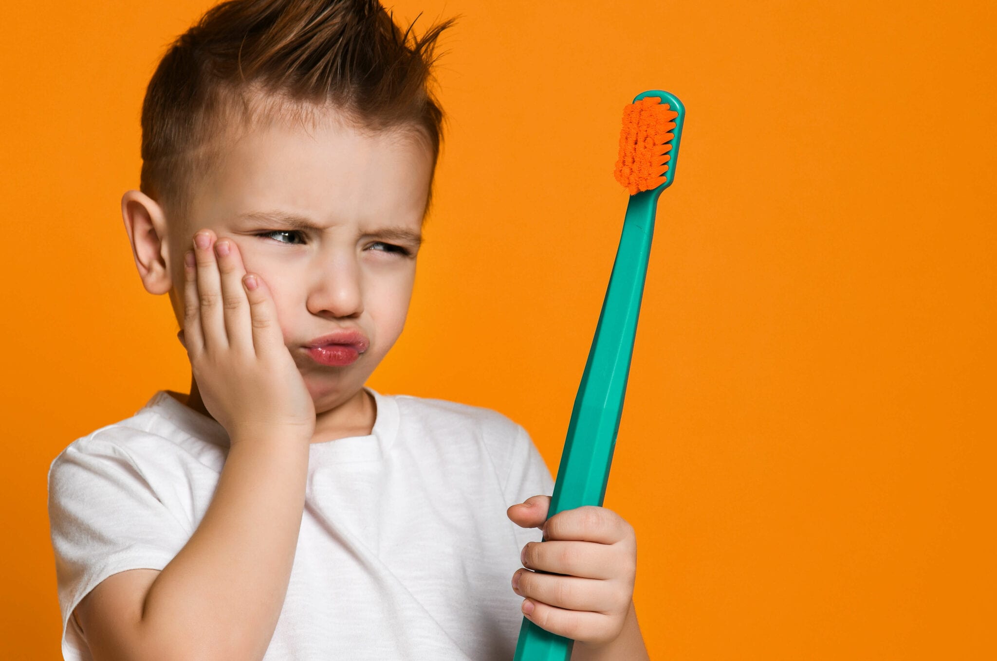 Boy has a toothache and looks at toothbrush