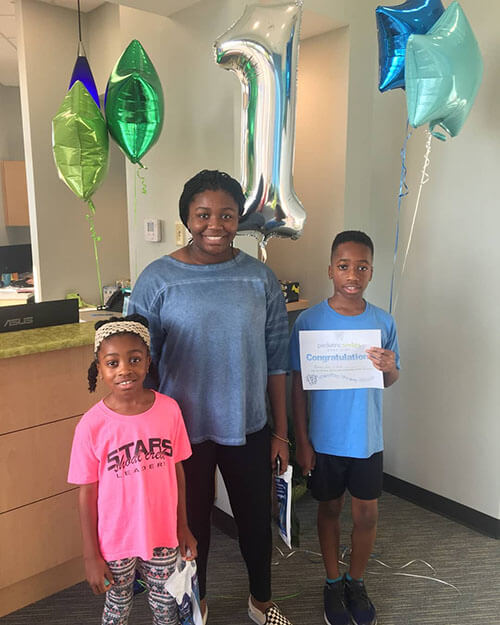 Family poses for picture with "congratulations" award for completion
