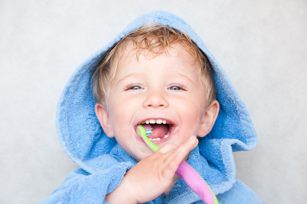 Happy child smiles while brushing teeth
