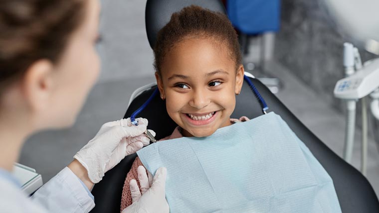 Girl Smiles At Dentist After Receiving Pediatric Dental Crown