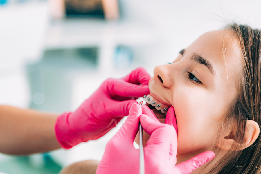 Girl with braces having her teeth inspected by a dentist.
