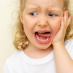 Girl with tooth pain holding the side of her face.