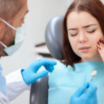Girl sitting in dentist’s chair holding the side of her face.