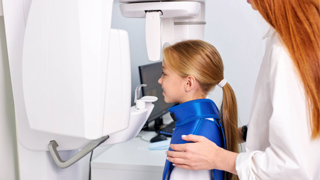 Girl preparing for a dental x-ray in front of the x-ray machine.