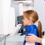Girl preparing for a dental x-ray in front of the x-ray machine.