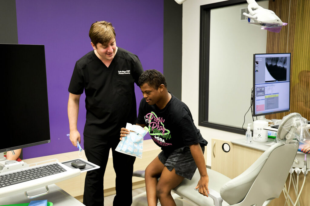 Dr. Dallin Roberts greets a young patient after a dental visit