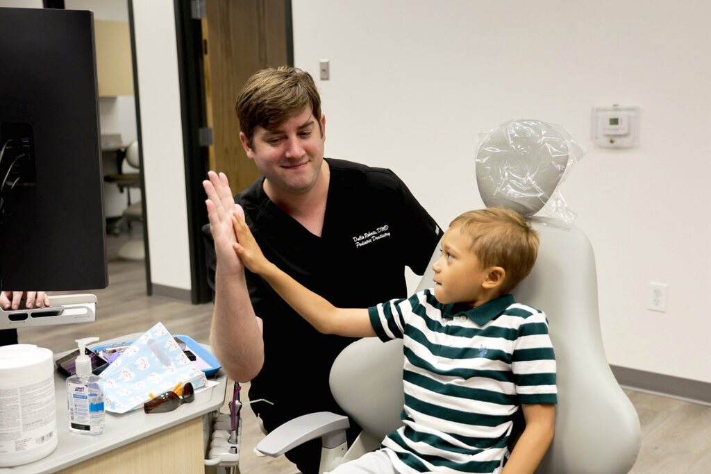 Dr. Dallin Roberts high-fives a young dental patient